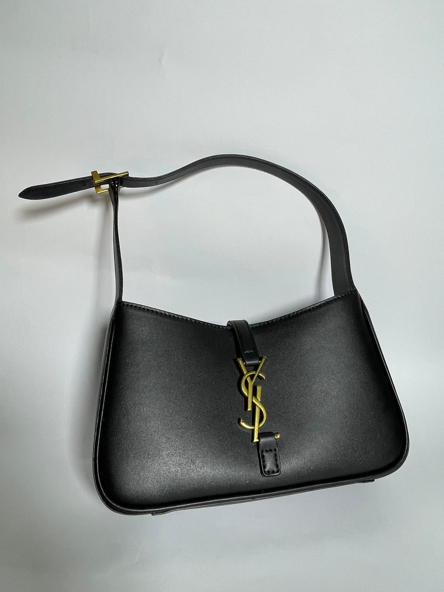 Black handbag with a gold logo on a light gray background