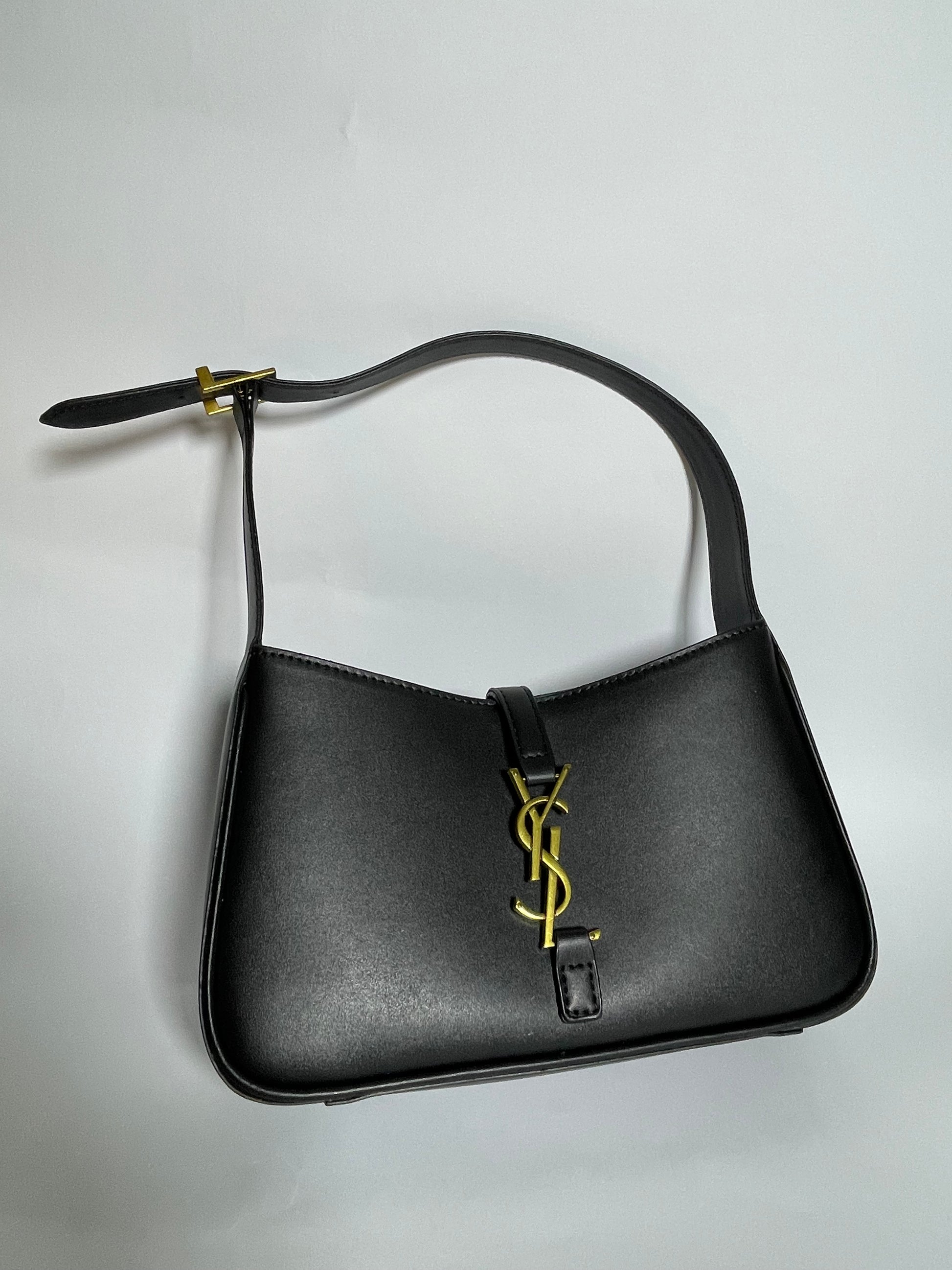 Black handbag with a gold logo on a light gray background